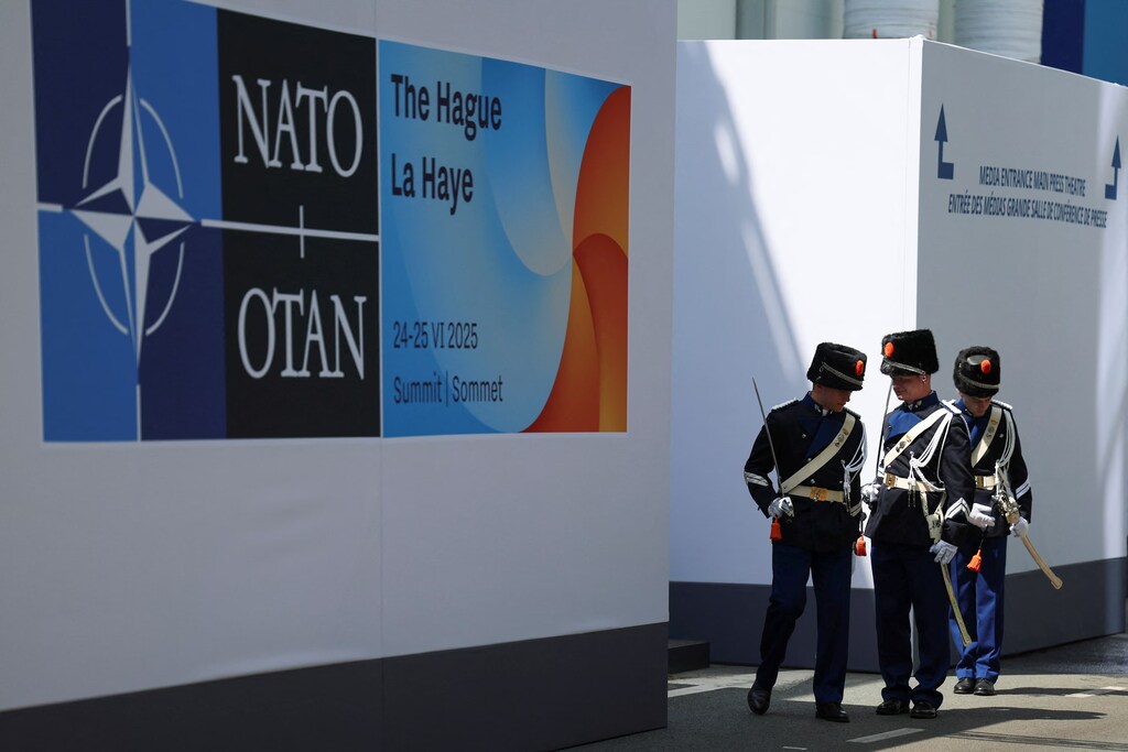Miembros del ejército con uniformes ceremoniales caminan en el lugar junto a un logotipo de la OTAN, el día de una cumbre de la OTAN en La Haya, Países Bajos, el 25 de junio de 2025. REUTERS/Claudia Greco