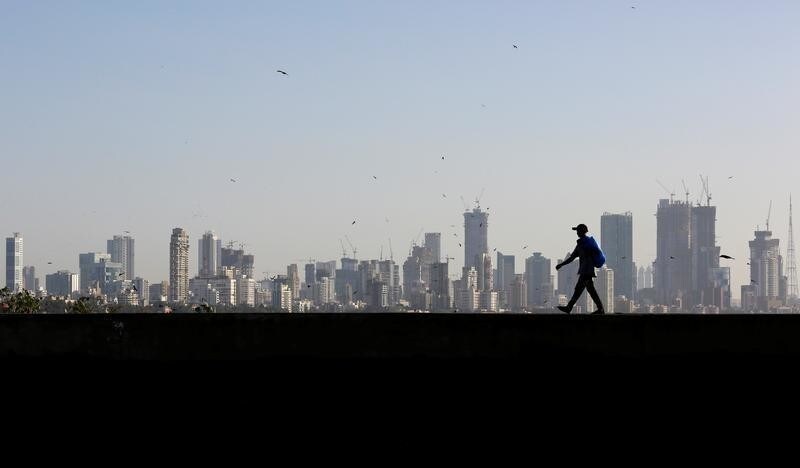 A man walks along a wall overlooking the central Mumbai's financial district skyline, India, March 9, 2017. REUTERS/Danish Siddiqui - RC15CEB7FBF0