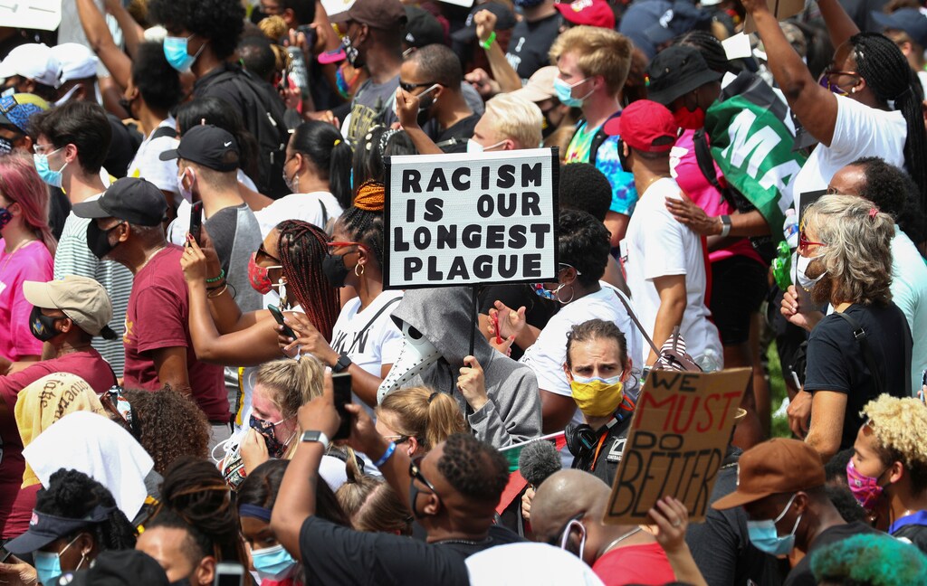Protestors stand with a sign reading "Racism is Our Longest Plague" at the "Get Your Knee Off Our Necks" Commitment March on Washington 2020 at the spot where Rev. Martin Luther King Jr delivered his "I Have a Dream" speech 57 years ago today in Washington, U.S., August 28, 2020. REUTERS/Tom Brenner - RC27NI957G52