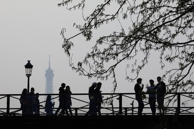 People walk across a bridge over the River Seine on a warm evening in Paris, France March 12, 2017. REUTERS/Kevin Coombs - RTX30PGI