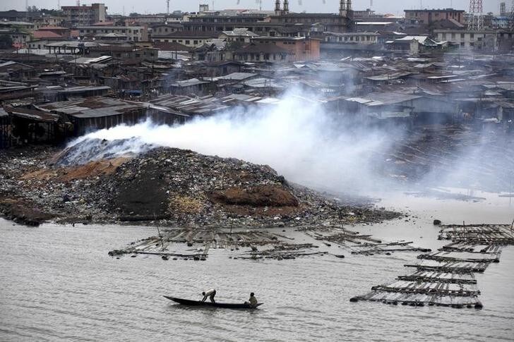 Smoke rises from the waste heap at a saw-mill at a lagoon near the Makoko Riverine Slum in Nigeria's commercial capital Lagos September 15, 2009. REUTERS/Akintunde Akinleye (NIGERIA ENVIRONMENT EMPLOYMENT BUSINESS)