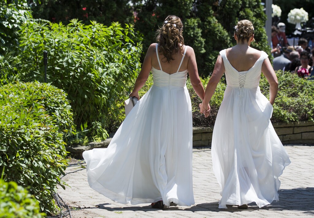 A couple walks down a pathway to the "The Celebration of Love", a grand wedding where over 100 lesbian, gay, bisexual and transgender (LGBT) couples will get married, at Casa Loma in Toronto June 26, 2014. Toronto is hosting WorldPride, a week-long event that celebrates the LGBT community. REUTERS/Mark Blinch (CANADA - Tags: SOCIETY) - RTR3VYX3