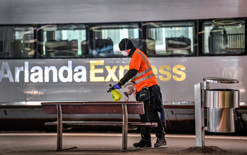 A cleaner wearing a face mask cleans a bench on a deserted platform for trains bound for Arlanda Airport, at Stockholm Central station, Sweden March 21, 2020. Very few passengers pass the Central station due to the coronavirus COVID-19 disease outbreak. TT News Agency/Anders Wiklund/via REUTERS ATTENTION EDITORS - THIS IMAGE WAS PROVIDED BY A THIRD PARTY. SWEDEN OUT. - RC2DOF91P2WV