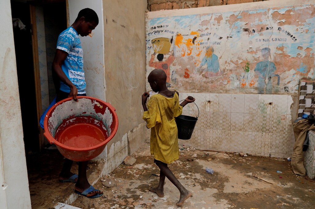 Moussa, a Koran student, called a talibe, from Futa, carries a bucket of water to take a shower at Maison de la Gare, an organisation that helps talibe street children reintegrate into society, in Saint-Louis, Senegal, February 7, 2019. "My parents know that I'm begging to take money back to the marabout (Koranic teacher) but they don't do anything. I don't like to beg but I'm forced. I'm being beaten up if I don't take money back," Moussa said. REUTERS/Zohra Bensemra SEARCH "TALIBE BENSEMRA" FOR THIS STORY. SEARCH "WIDER IMAGE" FOR ALL STORIES. - RC110AD9CD70