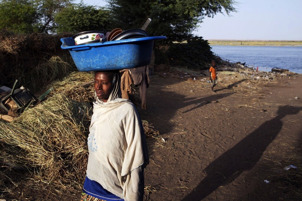 A woman carries a pail on her head after washing dishes in the Niger River in Gao February 20, 2013. REUTERS/Joe Penney (MALI - Tags: SOCIETY) - RTR3E152