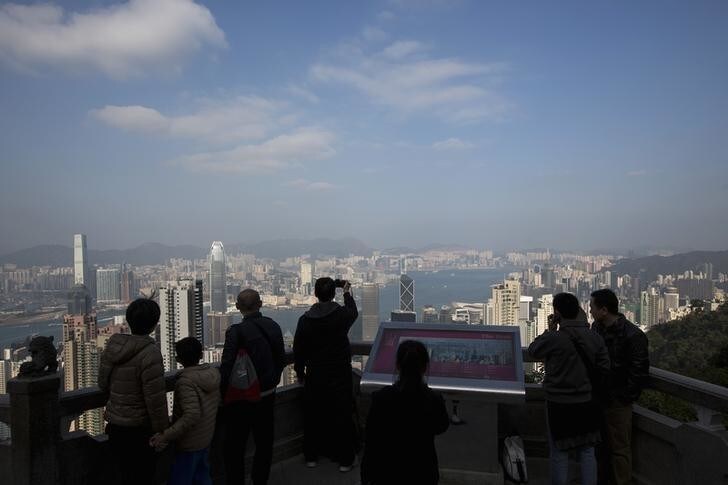 Mainland Chinese tourists view the Hong Kong skyline at the Peak in Hong Kong January 14, 2014. Launched by the Hong Kong government over a decade ago to stimulate an economy battered by the Severe Acute Respiratory Syndrome (SARS) crisis, the Hong Kong Capital Investment Entrant Scheme has proved a hit with mainland Chinese who, though technically barred, see it as a means to invest money near home without the tight controls imposed by Beijing. Although governed by Beijing, Hong Kong has a high degree of autonomy. Picture taken January 14, 2014. REUTERS/Tyrone Siu (CHINA - Tags: POLITICS BUSINESS SOCIETY IMMIGRATION CITYSCAPE TRAVEL)
