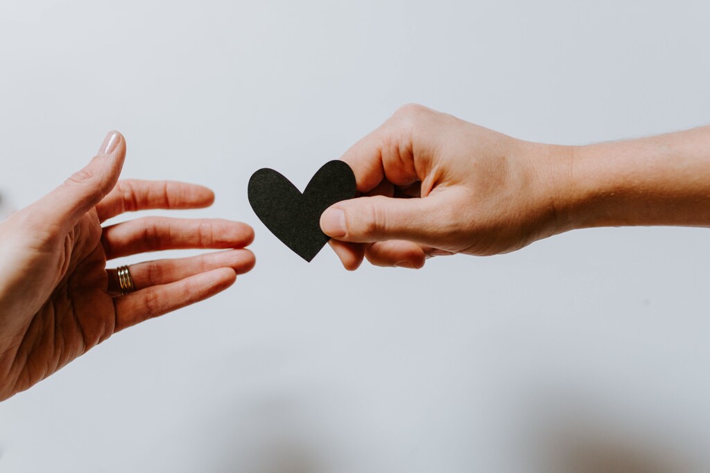 A man handing a woman a paper heart