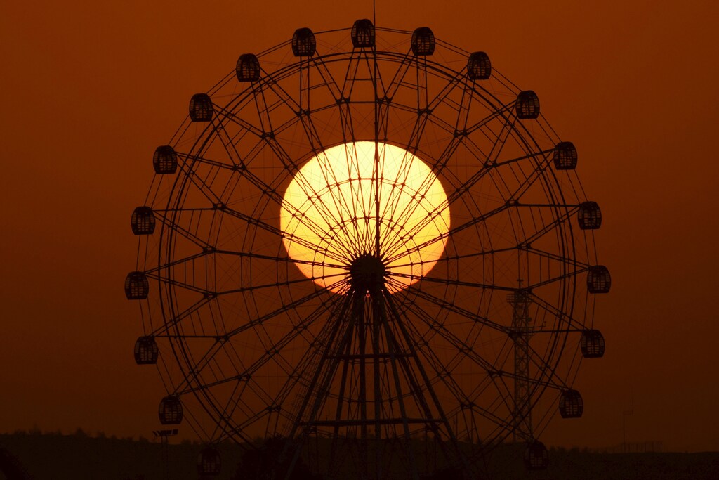 The sun is seen rising behind a skywheel in Korla, Xinjiang Uighur Autonomous Region, November 10, 2015.