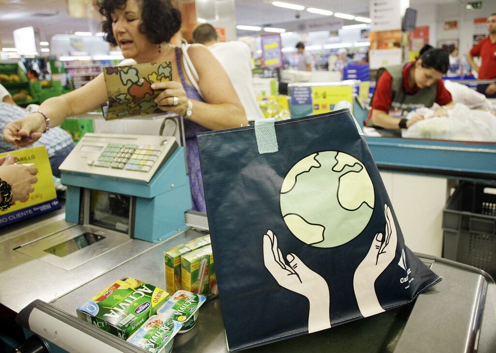 A customer purchases one of Carrefour's new reusable bags at a Carrefour supermarket in Madrid September 1, 2009. The French supermarket chain plans to remove all of its plastic bags from all of its Spanish stores by the end of 2009. To replace the plastic bags they offer customers a biodegradable bag at 0.05 euros ($0.07) or a raffia reusable bag at 0.25 euros ($0.3). REUTERS/Susana Vera (SPAIN SOCIETY BUSINESS ENVIRONMENT)