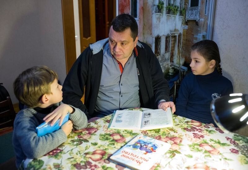 Doctor Dmitriy Rozumiy helps his children with their homework in the village of Markhalivka, Ukraine, January 30, 2018.