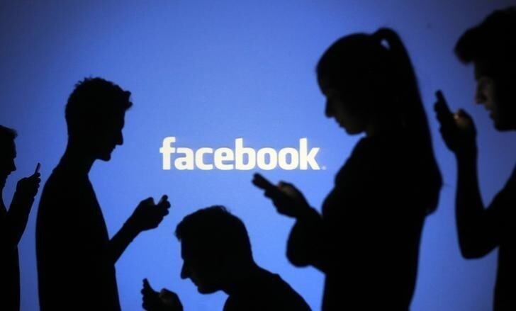 People are silhouetted as they pose with laptops in front of a screen projected with a Facebook logo, in this picture illustration taken in Zenica October 29, 2014. Facebook Inc warned on Tuesday of a dramatic increase in spending in 2015 and projected a slowdown in revenue growth this quarter, slicing a tenth off its market value. Facebook shares fell 7.7 percent in premarket trading the day after the social network announced an increase in spending in 2015 and projected a slowdown in revenue growth this quarter. REUTERS/Dado Ruvic (BOSNIA AND HERZEGOVINA - Tags: BUSINESS SCIENCE TECHNOLOGY BUSINESS LOGO)