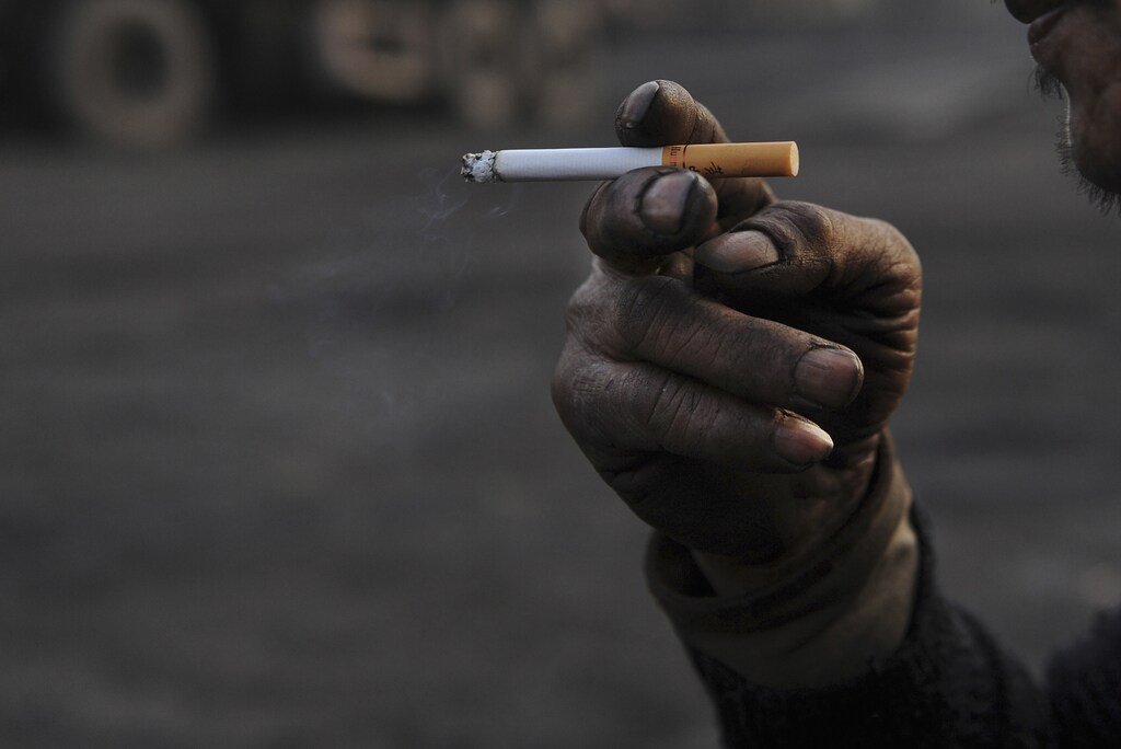 A worker smokes a cigarette during a break at a coal freight yard in Hefei, Anhui province, January 13, 2013. REUTERS/Stringer (CHINA - Tags: SOCIETY) - GM1E91D1E2401