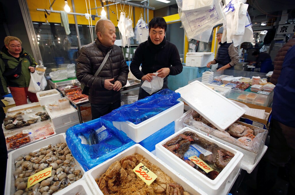 Masatoshi Fukutsuna, chef and owner of sushi restaurant Eiraku, chats with a wholesaler at Toyosu Fish Market in Tokyo, Japan December 11, 2018. Picture taken December 11, 2018. To match Insight JAPAN-SUSHI/LAST-RESTAURANT. REUTERS/Issei Kato - RC1696A278F0