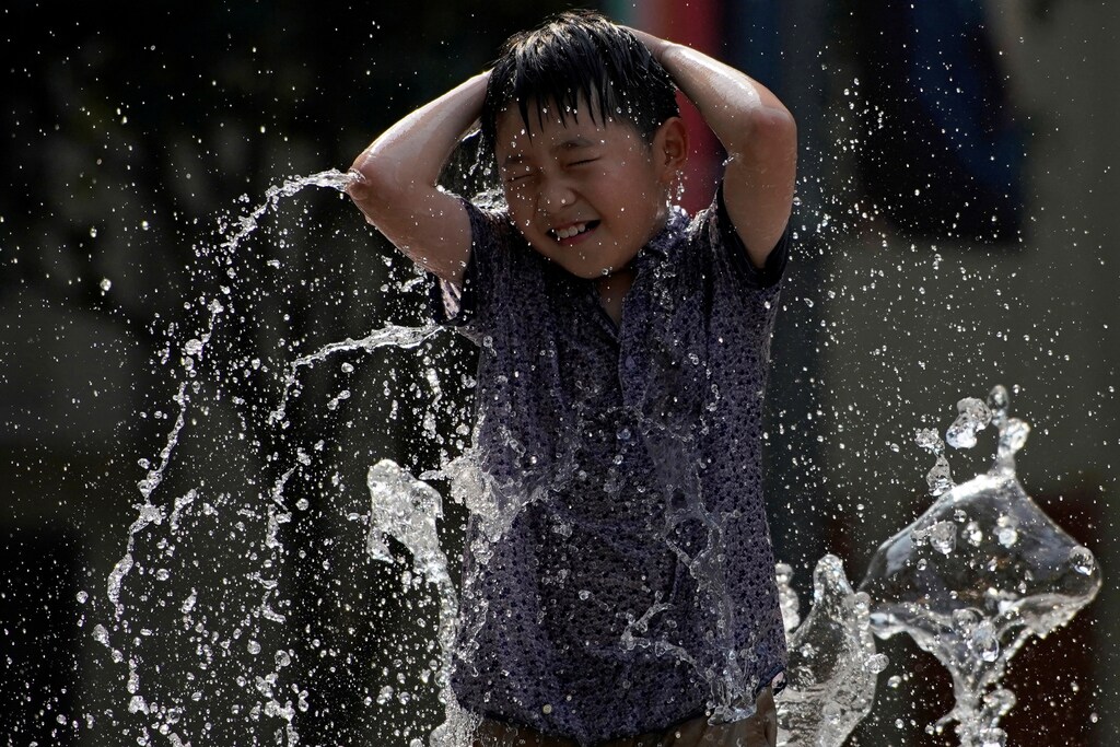 A child cools off from hot weather in a fountain in Shanghai, China July 25, 2017. REUTERS/Aly Song - RTX3CTEE