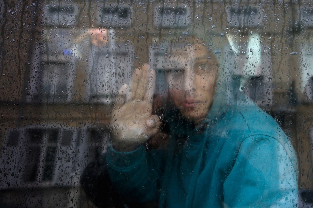 An adolescent Afghan migrant waves from a van as he departs with six others from the emergency shelter for minors in Saint Omer, France as they leave for Britain October 18, 2016. REUTERS/Pascal Rossignol - RTX2PANQ