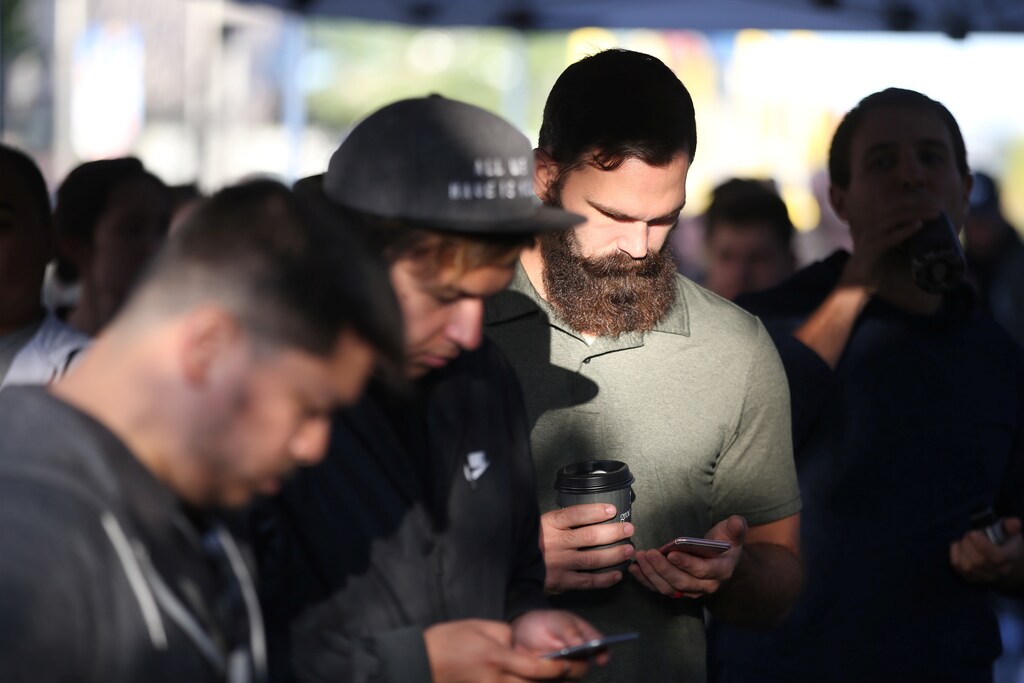 People browse their phones as they wait in line to buy the new iPhone 7 smartphone outside an Apple Inc. store in Los Angeles, California, U.S., September 16, 2016. REUTERS/Lucy Nicholson - RTSO2RT
