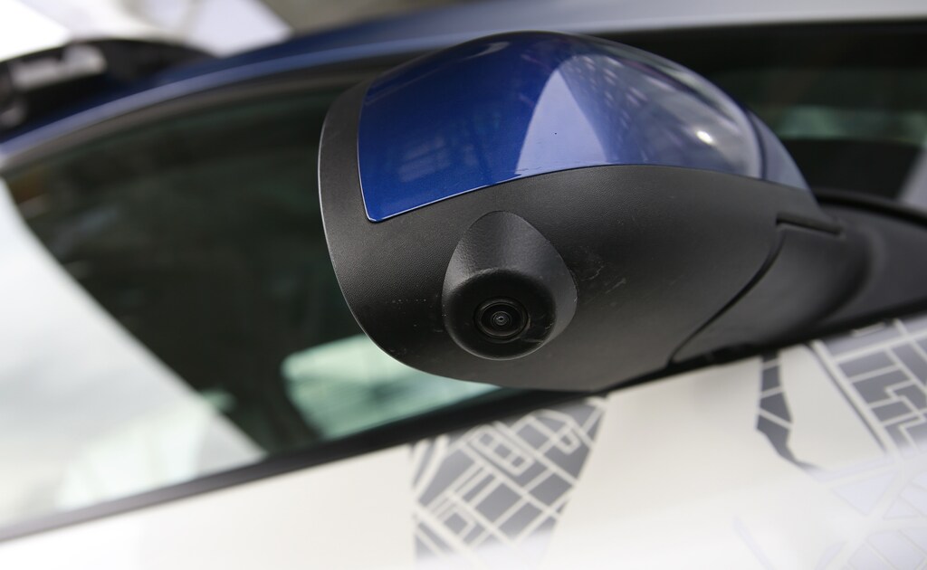 A navigational camera on the wing-mirror of a modified Nissan Leaf, a driverless car