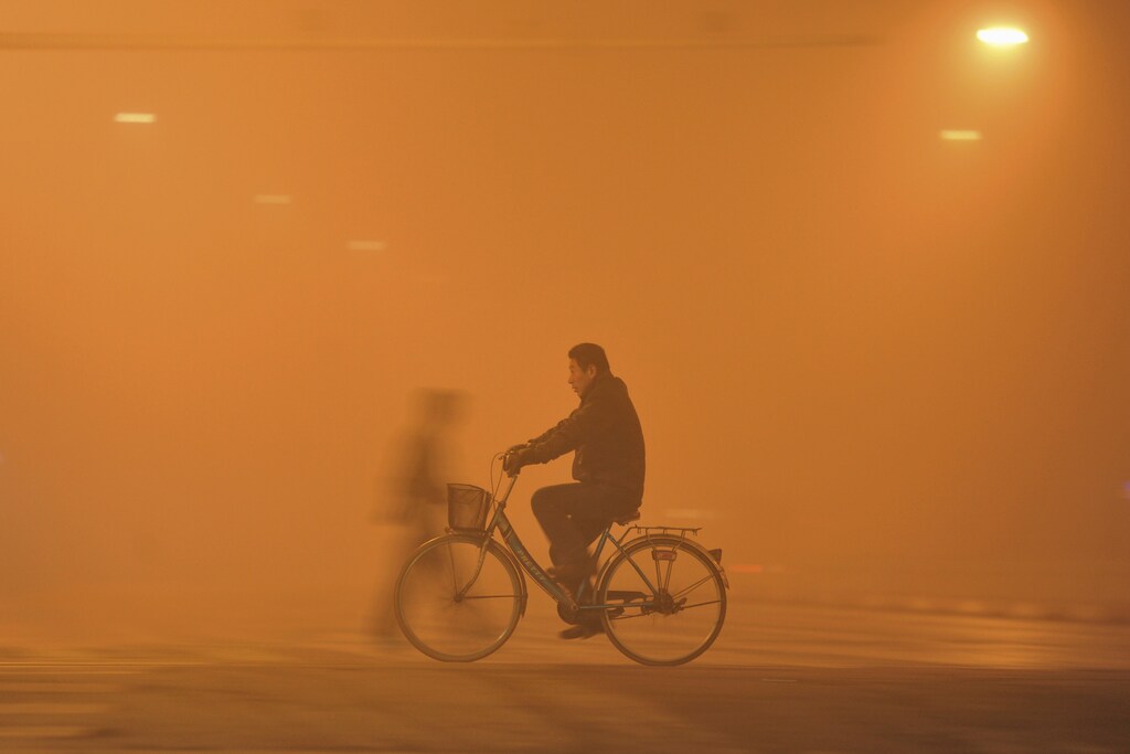 A man rides his bicycle across a street amid heavy haze in Fuyang, Anhui province, China, November 30, 2015. Heavy smog and thick fog engulfed many parts of northern and eastern China on Monday, local media reported. REUTERS/Stringer CHINA OUT. NO COMMERCIAL OR EDITORIAL SALES IN CHINA. - GF20000079329