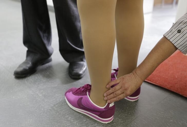 A woman touches an ankle on Qian Hongyan's new prosthesis at China Rehabilitation Centre in Beijing, September 5, 2013. Qian, who has been moving by using a basketball after she lost her legs in a car accident at age four, got her new free prosthesis fitted for her adult body. She first received artificial limbs in 2005 and later joined a swimming club for the handicapped and became an athlete. REUTERS/Jason Lee (CHINA - Tags: SOCIETY HEALTH)