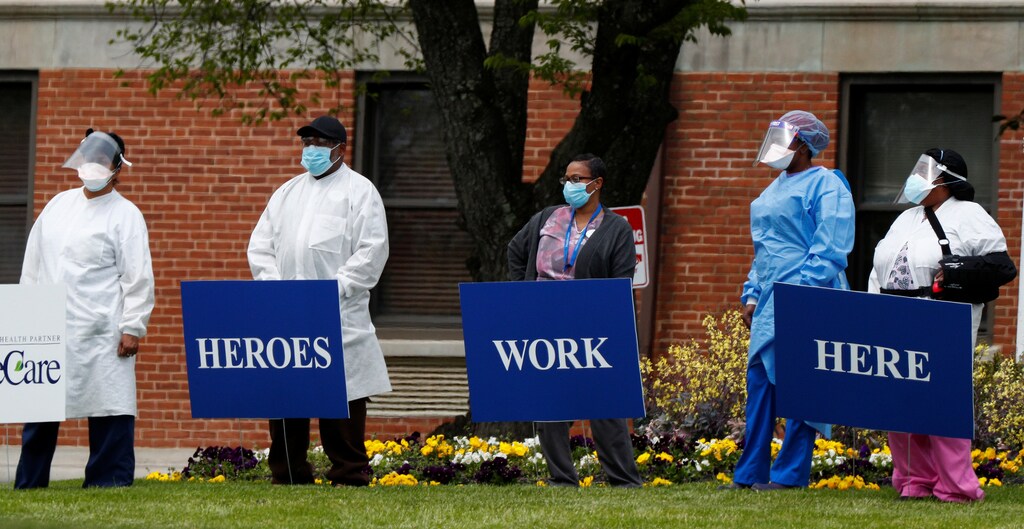Medical workers pose for photos taken by coworkers as they stand with signs saying "Heroes Work Here" that have been placed outside the FutureCare Lochearn senior nursing facility where a large number of residents and staff have reportedly tested positive following a coronavirus (COVID-19) disease outbreak at the facility in Baltimore, Maryland, U.S. April 17, 2020.