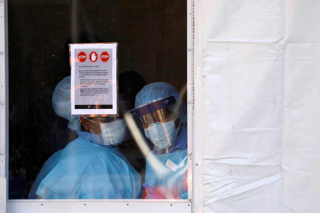 Health workers in protective gear peer from a tent which was constructed to test people for the coronavirus disease (COVID-19) outside the Brooklyn Hospital Center in Brooklyn, New York City, U.S., March 27, 2020. REUTERS/Andrew Kelly - RC2ESF9VPJJ5 - RC2LSF9P1LX1