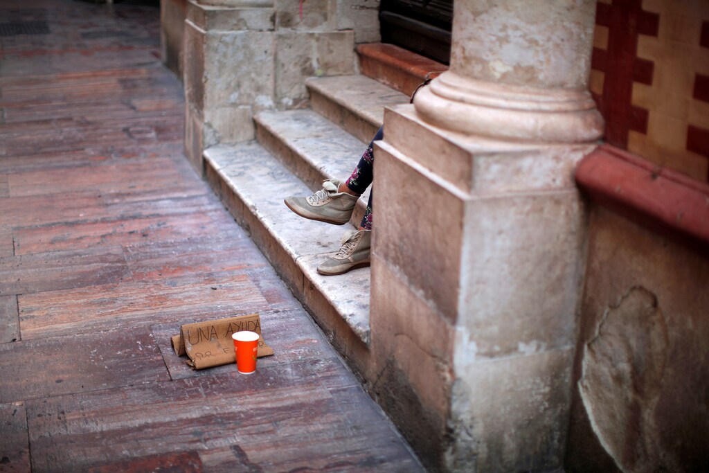 A beggar asks for alms during the International Day for the Eradication of Poverty in downtown Malaga, Spain October 17, 2016. The signs reads, "A help, please". REUTERS/Jon Nazca - RTX2P89Q
