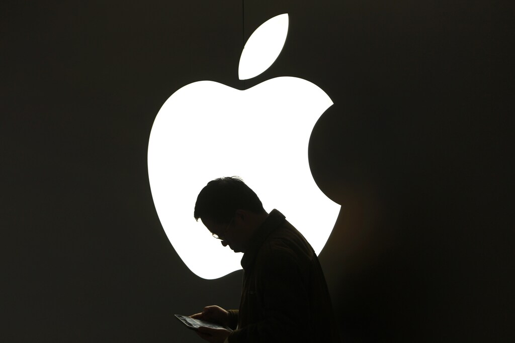 A man looks at his Apple iPad in front an Apple logo outside an Apple store in downtown Shanghai March 16, 2012. REUTERS/Aly Song (CHINA - Tags: BUSINESS TPX IMAGES OF THE DAY) - RTR2ZFTV