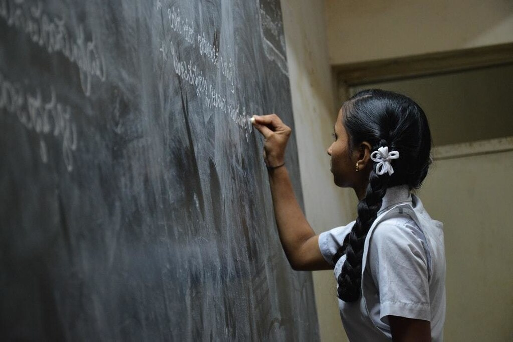 image of a young girl writing on a blackboard at school