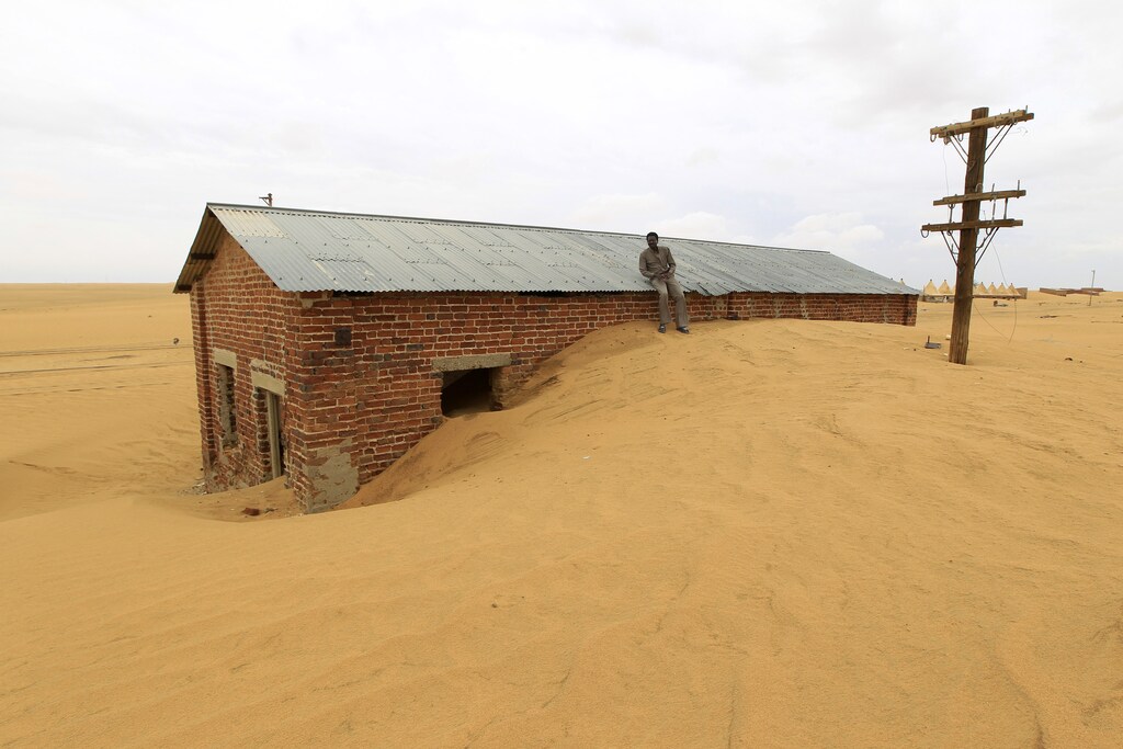 A worker rests on the roof of a building surrounded by sand as a result of desert encroachment at Ogrein Railway Station at the Red Sea State August 1, 2013. REUTERS/ Mohamed Nureldin Abdallah (SUDAN - Tags: ENVIRONMENT SOCIETY TPX IMAGES OF THE DAY) - GM1E9820N8101