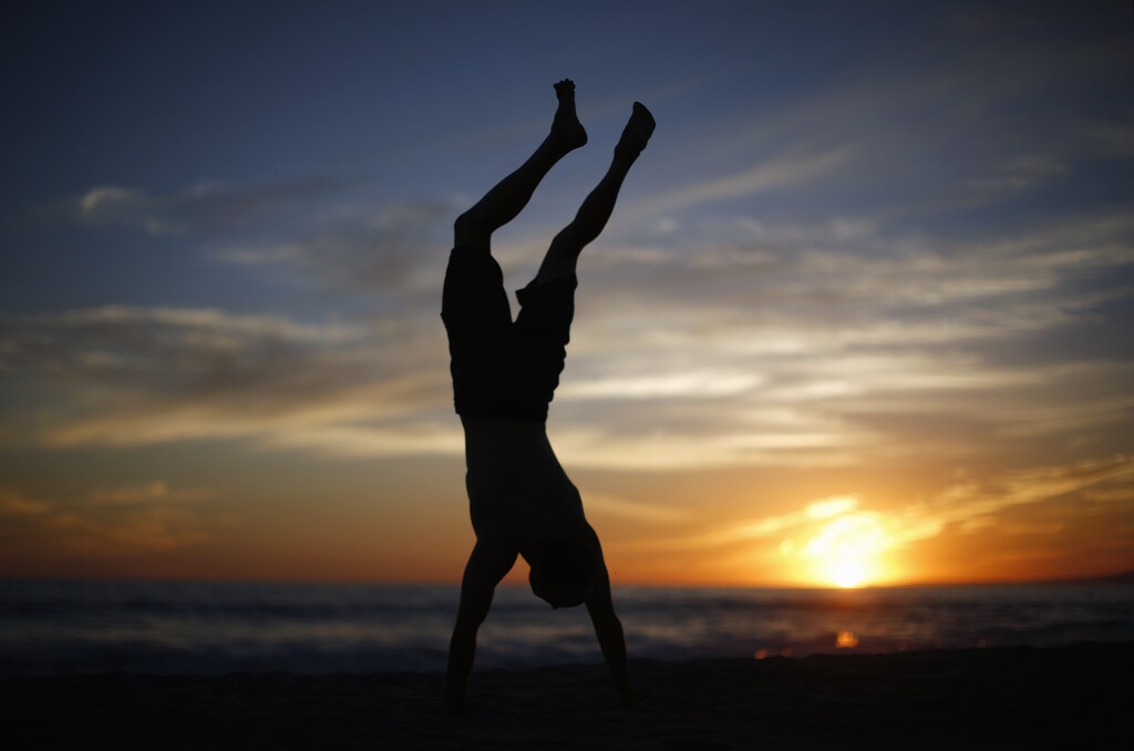 A man does a handstand as the sun sets over the Pacific Ocean on the beach in Santa Monica, California October 3, 2014. Southern California sizzled in a heat wave as temperatures soared above 100 degrees Fahrenheit in parts of Los Angeles. REUTERS/Lucy Nicholson (UNITED STATES - Tags: ENVIRONMENT SOCIETY) - GM1EAA40UQZ01