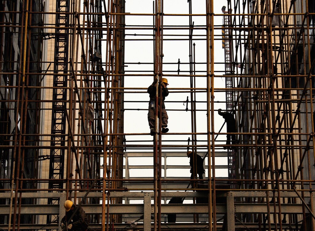 Construction workers stand on scaffolding at a building site in the financial district of Beijing November 18, 2008. China's labour ministry has told local governments not to increase minimum wages in order to avoid putting any additional pressure on companies already feeling the pinch of the global credit crisis, state media said on Monday. REUTERS/David Gray (CHINA) - GM1E4BI0ZXH01