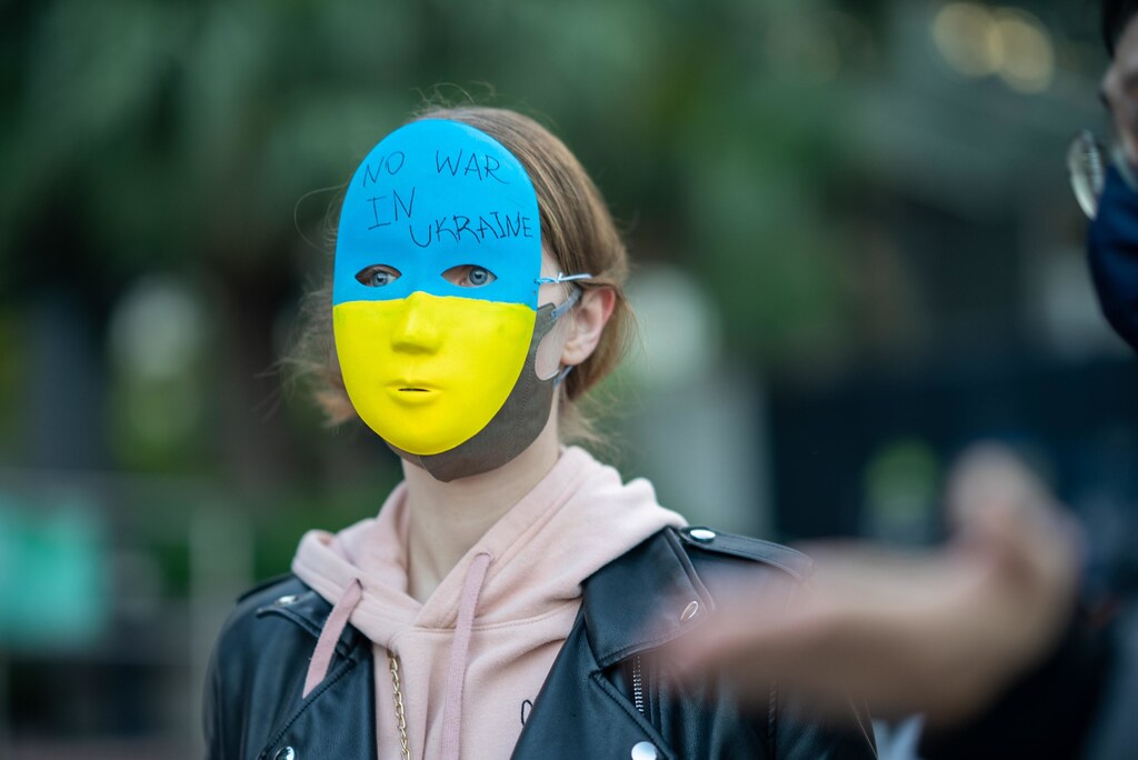 A person wearing a mask decorated with Ukraine's flag and the words "No war in Ukraine".