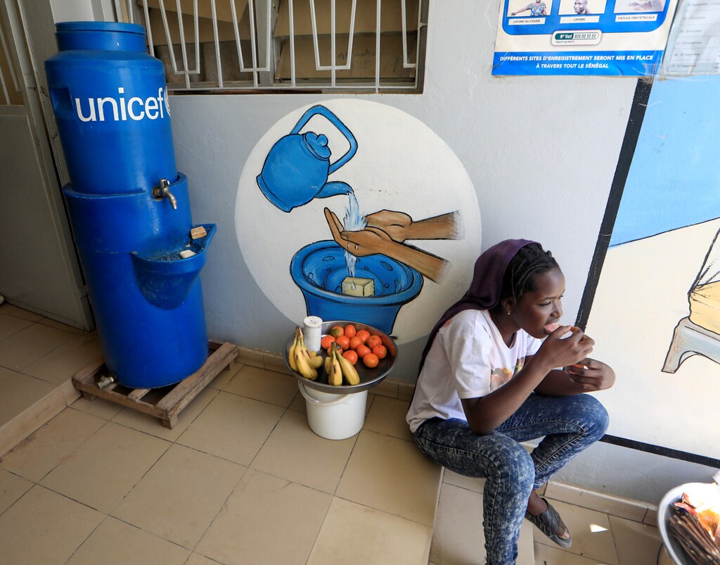 A girl eats as she sits next to a handwashing station, while she sells fruits at the entrance of a medical center in Pikine, on the outskirts of Dakar, Senegal March 9, 2020. Picture taken March 9, 2020. REUTERS/Zohra Bensemra - RC2RLF9CL1JQ