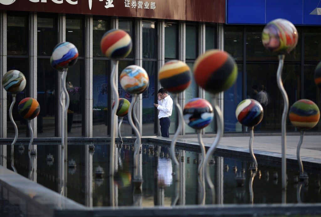 A man uses his mobile phone next an installation in a fountain at a financial district in Beijing October 21, 2014.