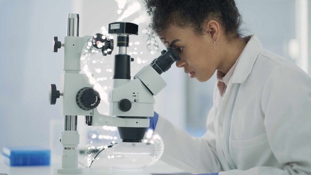 A scientist looking at a microscope researching cell therapies