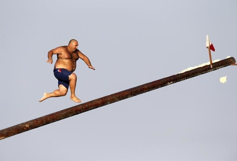 A man runs up the "gostra", a pole covered in grease, during the religious feast of St Julian, patron of the town of St Julian's, outside Valletta August 25, 2013. In the traditional "gostra", a game stretching back to the Middle Ages, young men, women and children have to make their way to the top and try to uproot one of the flags to win prizes. From May to September in Malta, there is hardly any weekend when a town or a village is not celebrating the feast of its patron saint or other saints revered in different churches.REUTERS/Darrin Zammit Lupi (MALTA - Tags: RELIGION SOCIETY TRAVEL TPX IMAGES OF THE DAY) MALTA OUT. NO COMMERCIAL OR EDITORIAL SALES IN MALTA - GM1E98Q0A7801