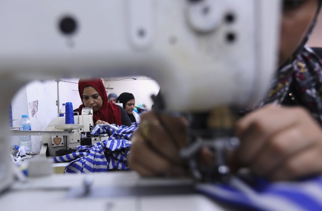 Egyptian women work as they sew school uniform inside a factory