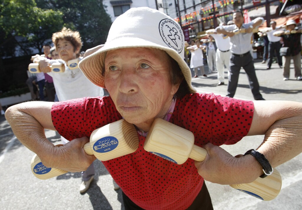 An elderly woman stretches using a pair of wooden dumbbells during a health promotion event to mark Japan's "Respect for the Aged Day" at a temple in Tokyo September 17, 2007. REUTERS/Issei Kato (JAPAN) - RTR1TXXA