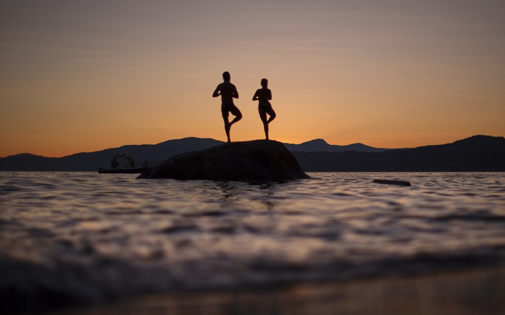 A couple stand on a rock facing the sunset along the shores of English Bay in Vancouver, British Columbia July 23, 2013. REUTERS/Andy Clark (CANADA - Tags: SOCIETY) - GM1E97O114A01