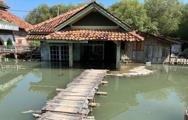 A flood-hit and sunken house that can only be accessed by a bamboo bridge is surrounded by rising waters in Demak, Indonesia