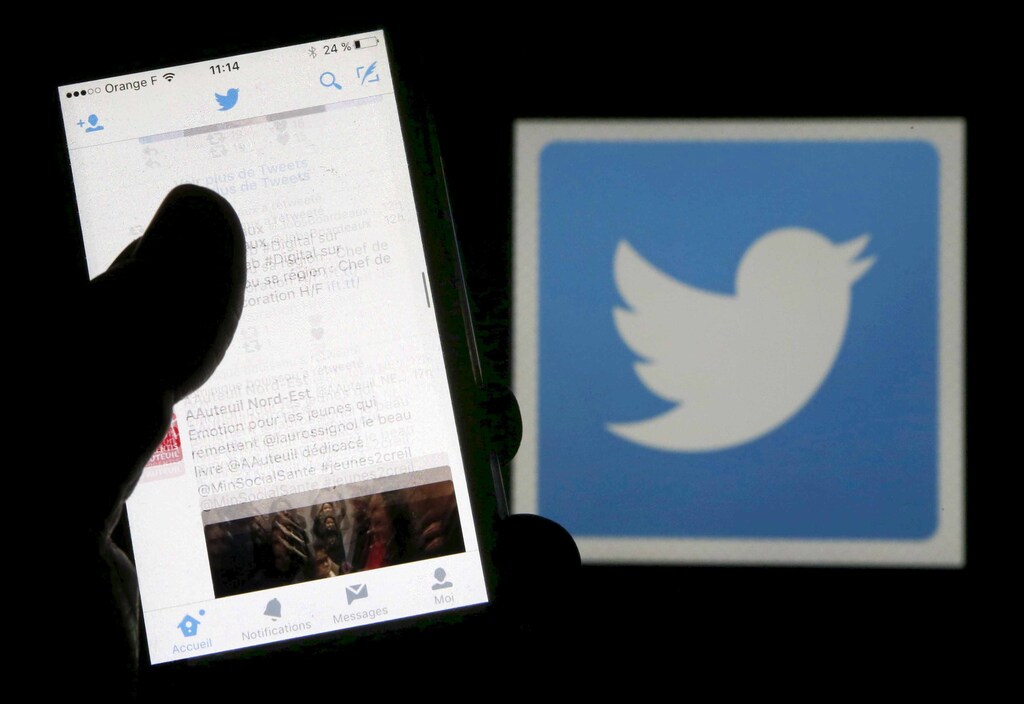 A man reads tweets on his phone in front of a displayed Twitter logo in Bordeaux, southwestern France, March 10, 2016. REUTERS/Regis Duvignau/Illustration/File Photo TPX IMAGES OF THE DAY - RTX2BSKW