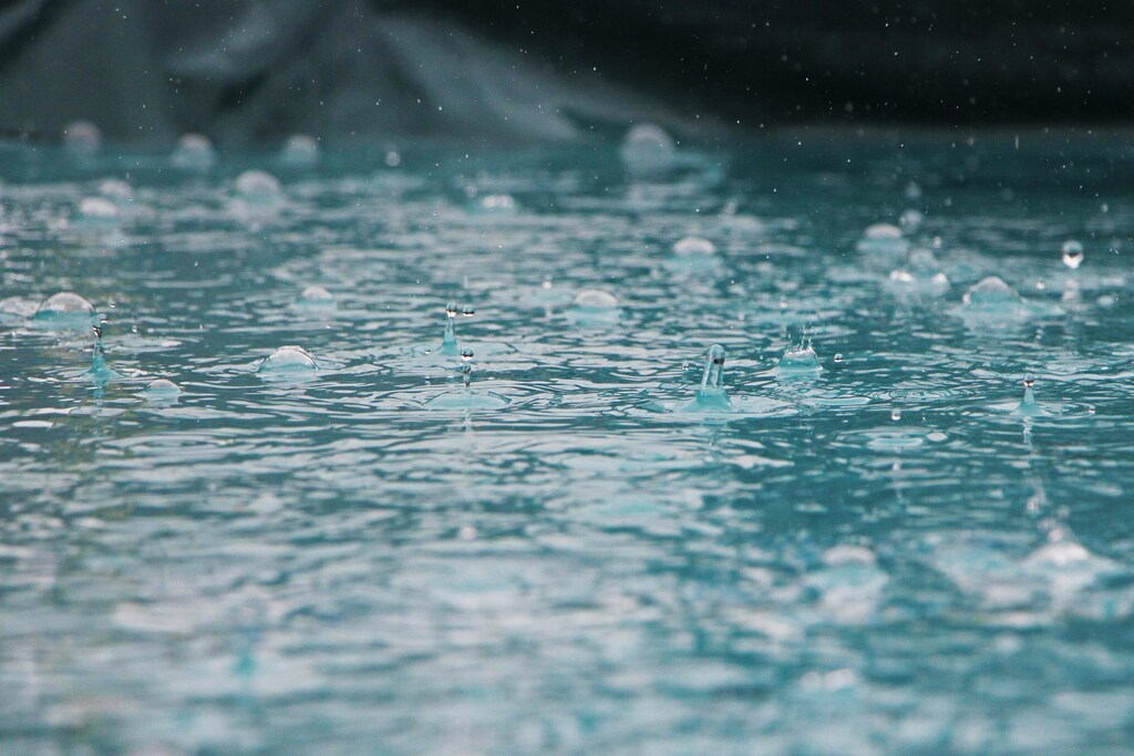 Rain falls down on a body of water