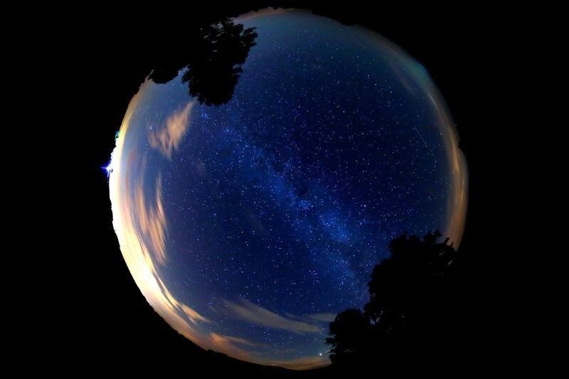A meteor (R) streaks past stars in the night sky during the Perseid meteor shower in Premnitz, west of Berlin, Germany, August 11, 2018. Picture taken with a fisheye lens.