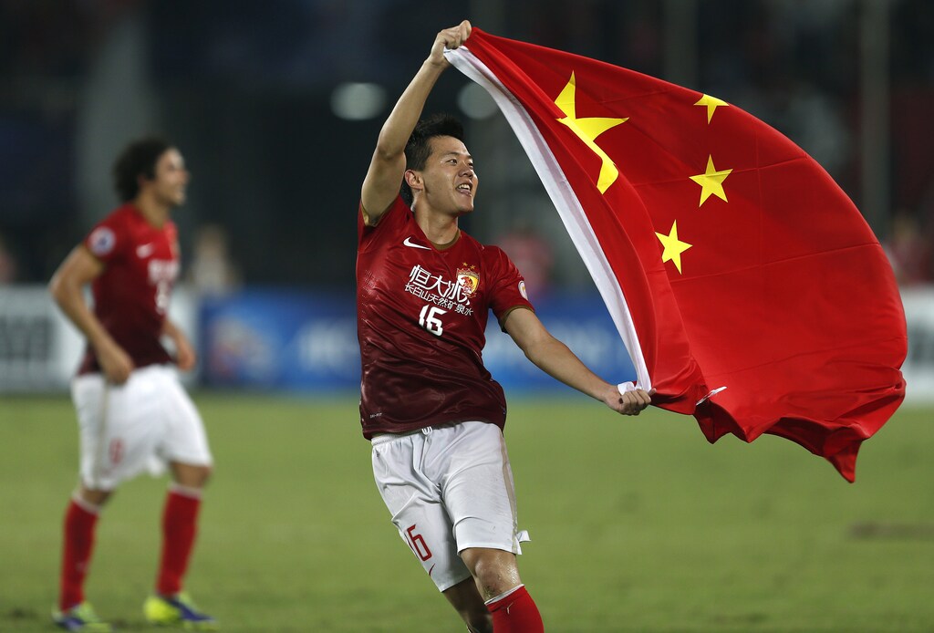 Huang Bowen (16) of China's Guangzhou Evergrande celebrates with the Chinese national flag after winning the team's final match of the AFC Champions' League against South Korea's FC Seoul at Tianhe stadium in the southern Chinese city of Guangzhou November 9, 2013.