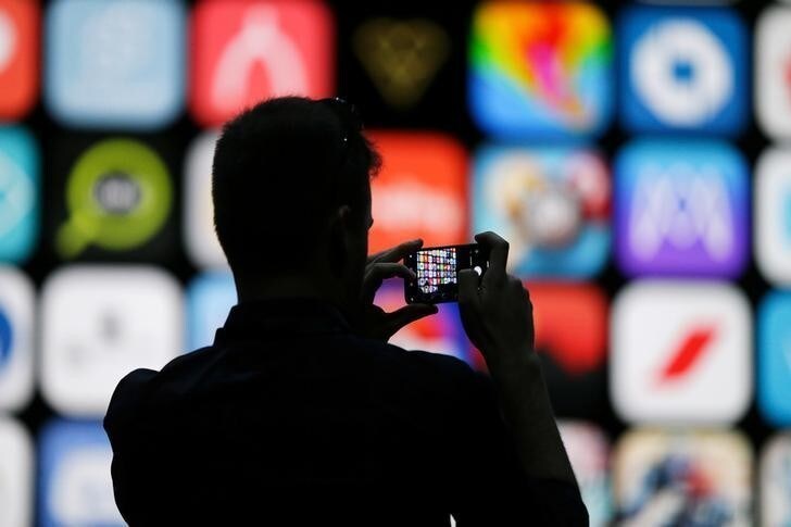 A visitor uses his iPhone X to take photos of the stage at the Apple Worldwide Developer conference in San Jose, California, U.S., June 4, 2018. REUTERS/Elijah Nouvelage
