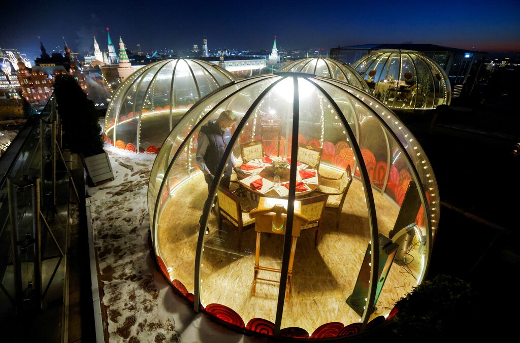 A waiter sets a table inside a transparent pod offered for private Christmas meals with backdrop of the Kremlin and Red Square on the rooftop of Ritz-Carlton hotel in Moscow, Russia December 8, 2020. Picture taken December 8, 2020. REUTERS/Maxim Shemetov TPX IMAGES OF THE DAY - RC2OJK9H6R4S