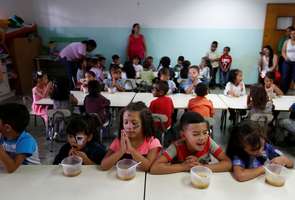 Students pray before eating their soup cooked for them during an activity for the end of the school year at the Padre Jose Maria Velaz school in Caracas, Venezuela July 12, 2016. Picture taken July 12, 2016. REUTERS/Carlos Jasso - RTSJKHG