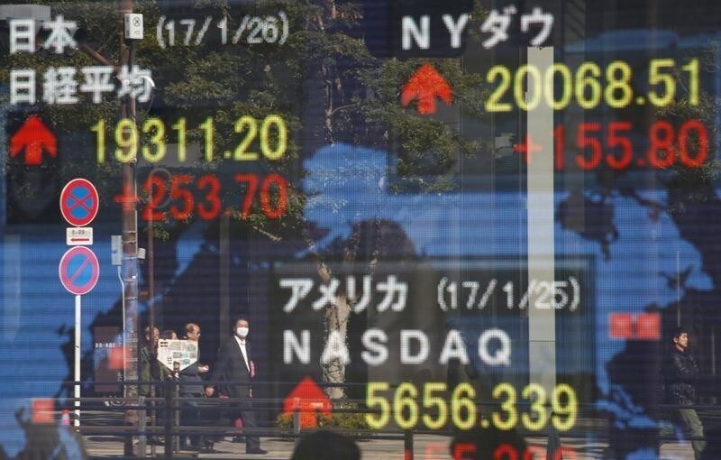 Pedestrians are reflected on an electronic board showing Japan's Nikkei average (top L), the Dow Jones average (top R) and the stock averages of other countries outside a brokerage in Tokyo, Japan, January 26, 2017. REUTERS/Kim Kyung-Hoon - RTSXE6U