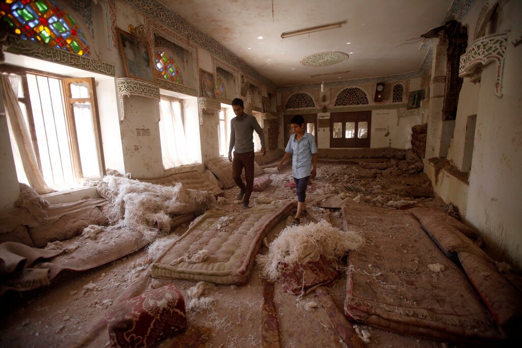 People walk on damaged furniture at damaged house destroyed by Saudi-led air strike in old Sanaa city, Yemen, September 24, 2016.