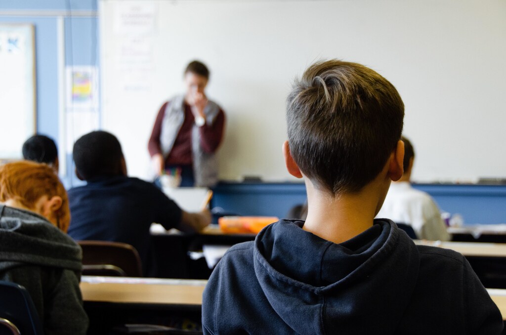 Students in a classroom being taught by a teacher.